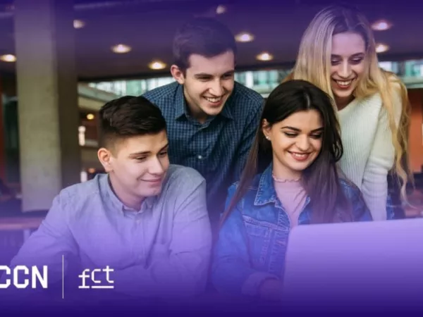 Grupo de jovens sorrindo e olhando para um laptop.